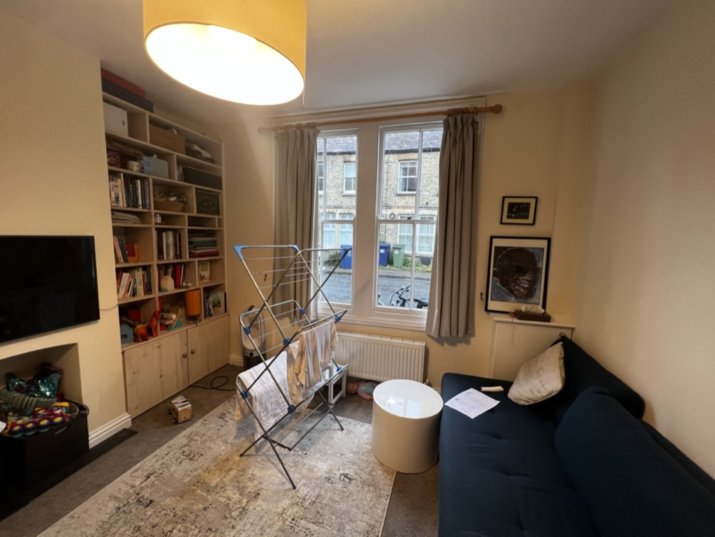 Cluttered front living room with dated shelving before renovation in Oxfordshire
