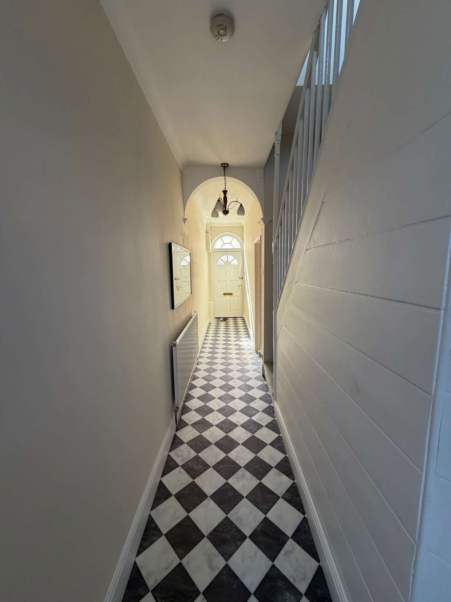 Refurbished entrance hallway with monochrome chequerboard tiling and panelled staircase in an Oxfordshire HMO conversion by RedFox Homes