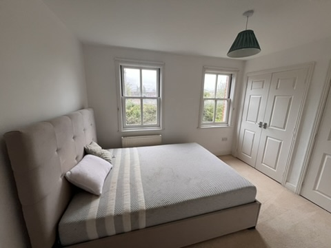 Empty guest bedroom with bare mattress before styling