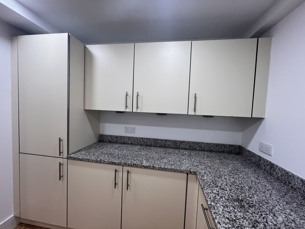 Bare cream kitchen units with granite worktop before finishing