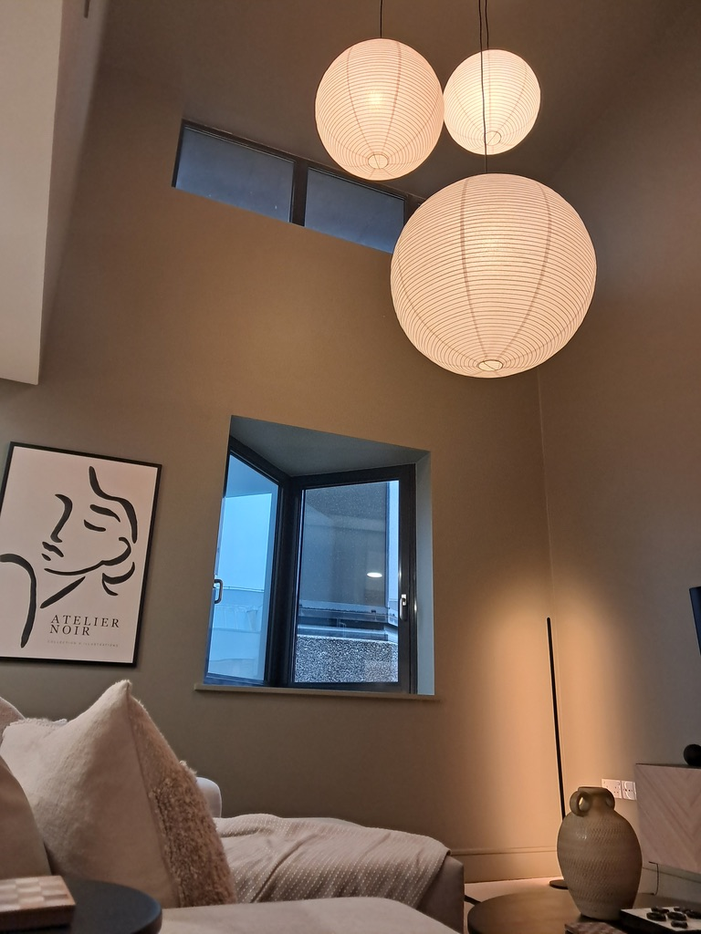 Styled double-height lounge with paper globe pendant lights after refurbishment
