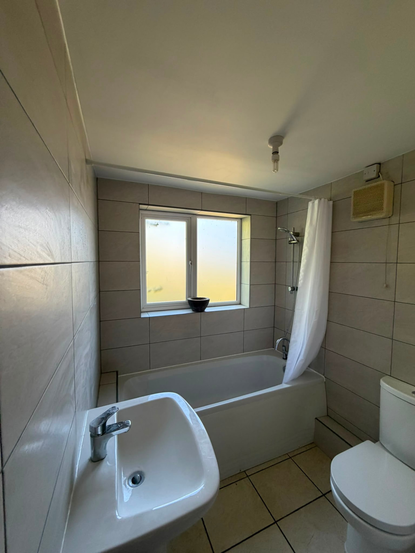 Finished tiled family bathroom with white bath after refurbishment